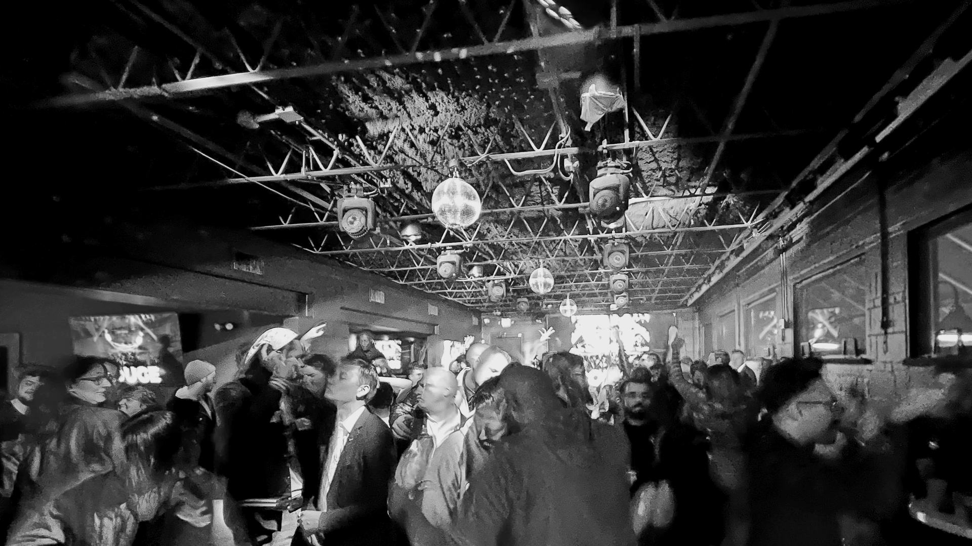 A full room late in the evening, lighting truss and a mirror ball overhead